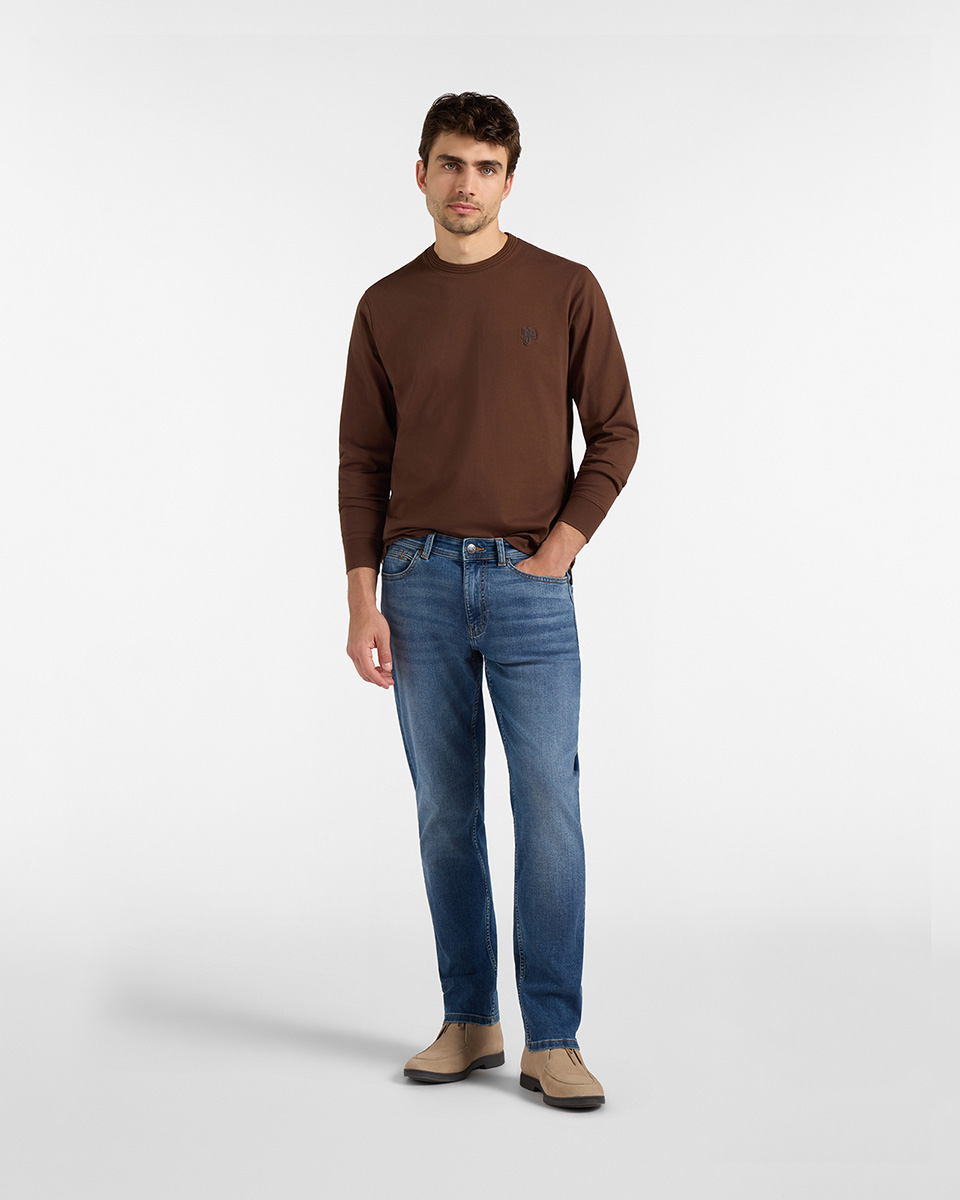For the HB Jeans trousers category, a model wears medium-wash blue straight-leg jeans paired with a dark brown long-sleeved shirt and beige suede desert boots against a white background.