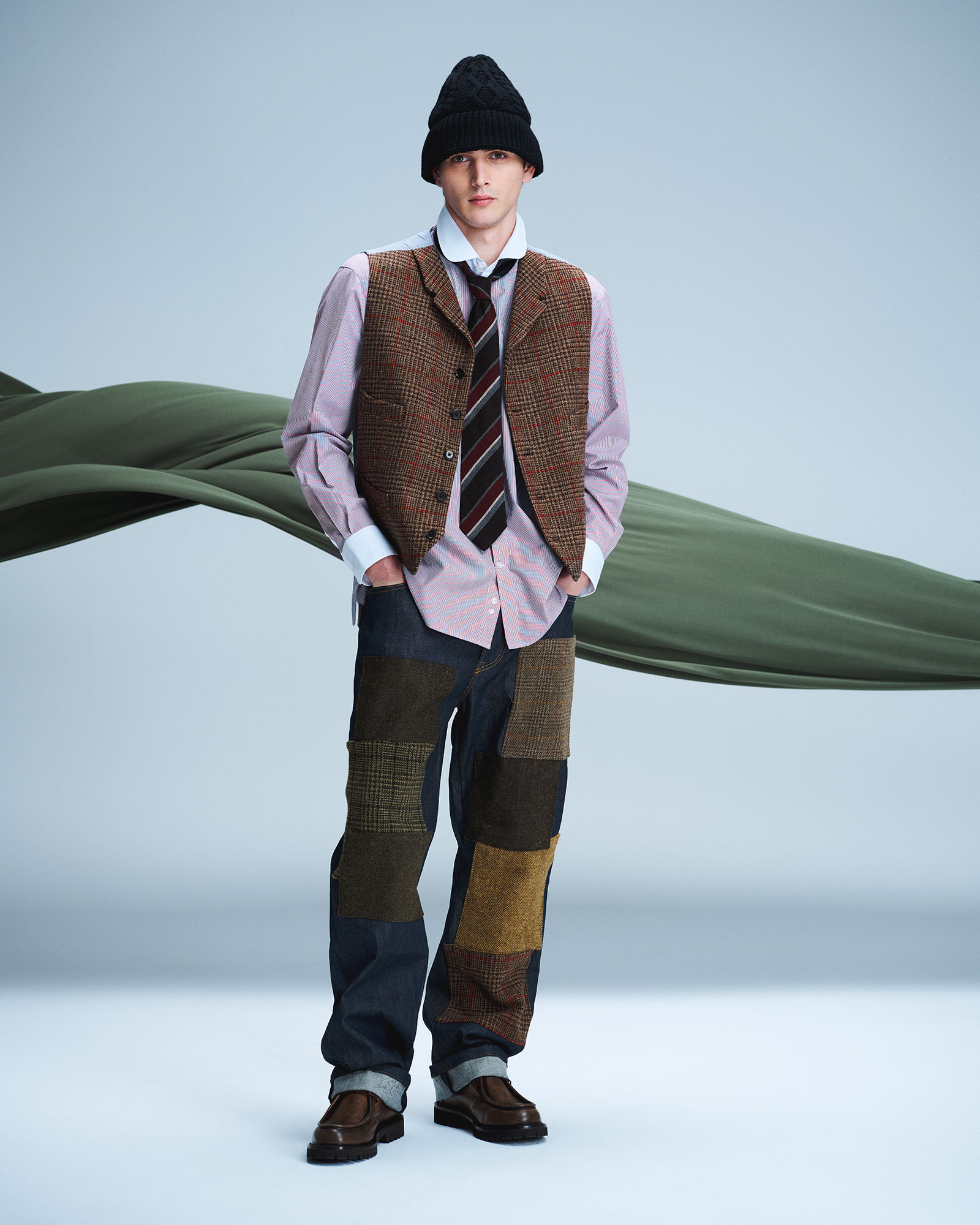 Man wearing shirt, checked vest and patchwork trousers with black beanie and loafers