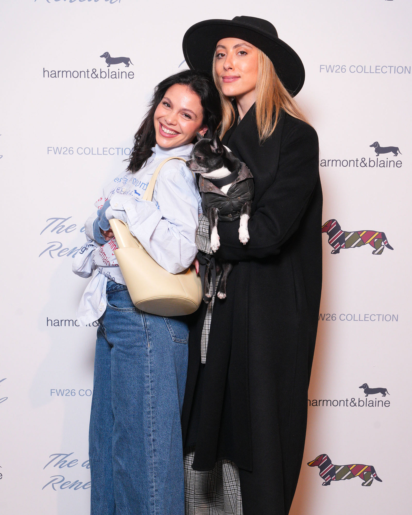 Two women in casual looks, one in wide jeans with beige bag, the other in black coat holding a dog