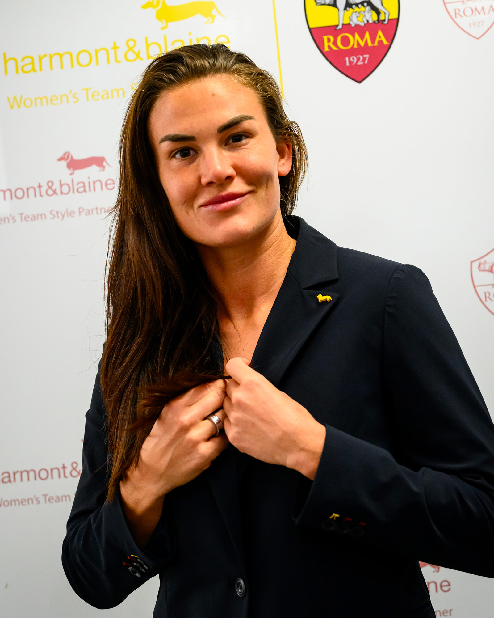 Woman wearing a navy blue blazer adjusting the lapel.