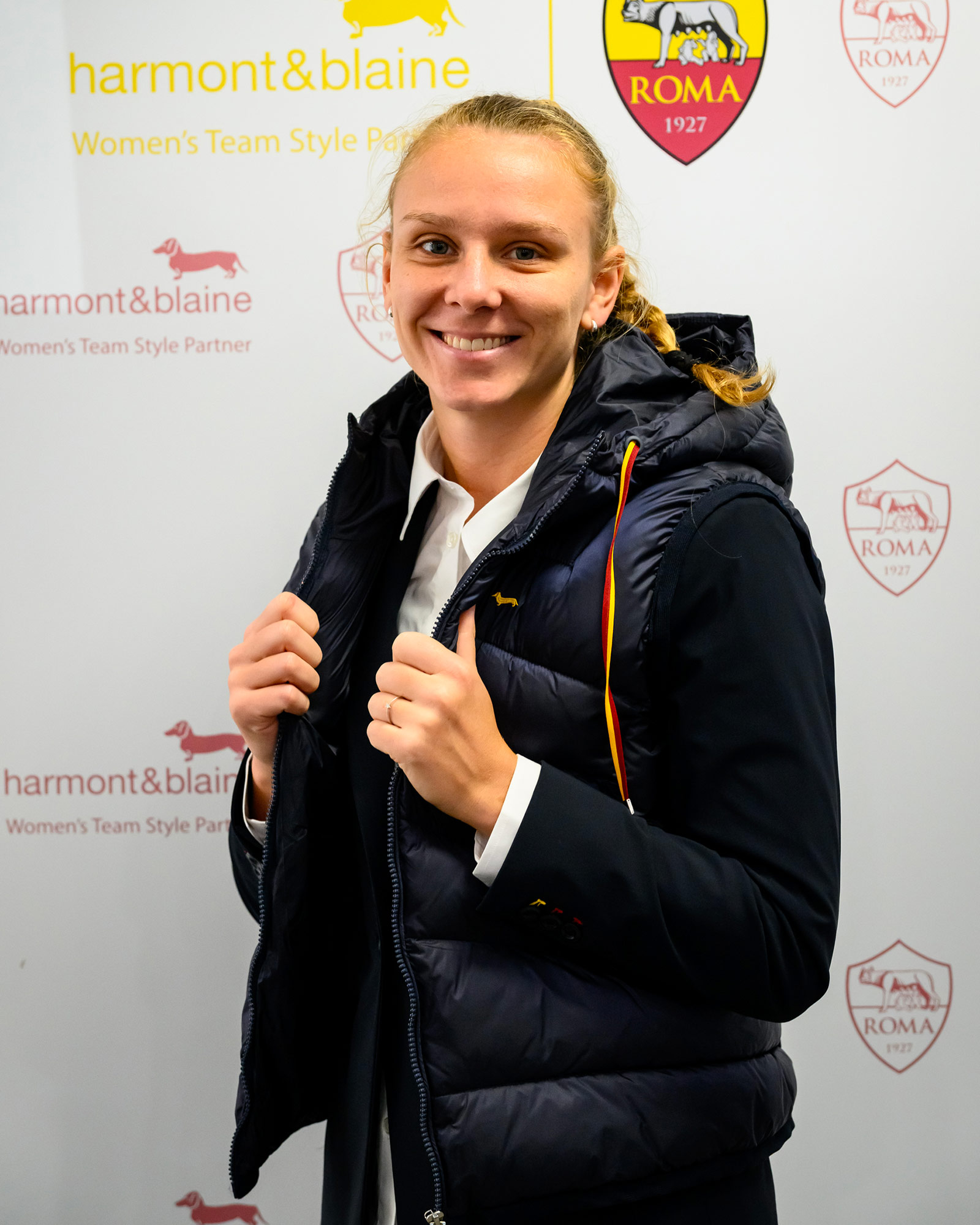 Woman wearing a navy padded vest over a formal jacket.