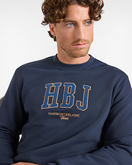 For the HB Jeans sweatshirts category, a model wears a dark blue crewneck sweatshirt featuring a large college-style "HBJ" logo with orange outlines and embroidered "HARMONT&BLAINE Jeans" text on the chest against a white background.