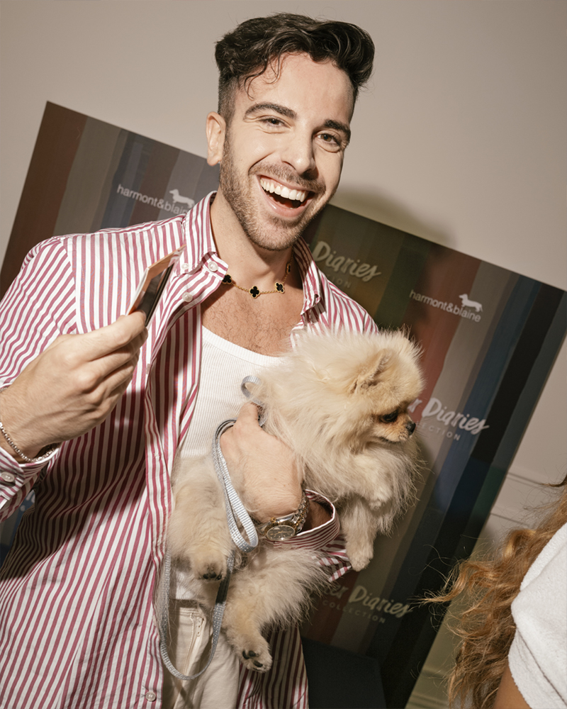 Hombre sonriente con perro en el evento Summer Diaries de Harmont & Blaine.