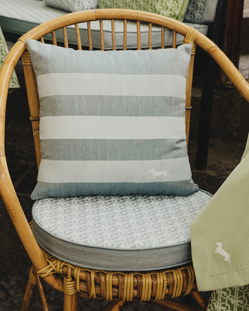Silla de rat&aacute;n con coj&iacute;n a rayas y logo de Harmont & Blaine.