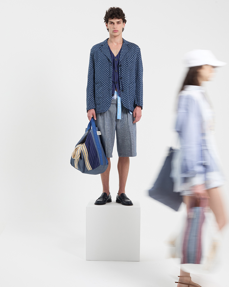 Modelo masculino con chaqueta azul y pantalones cortos de la colecci&oacute;n de verano.
